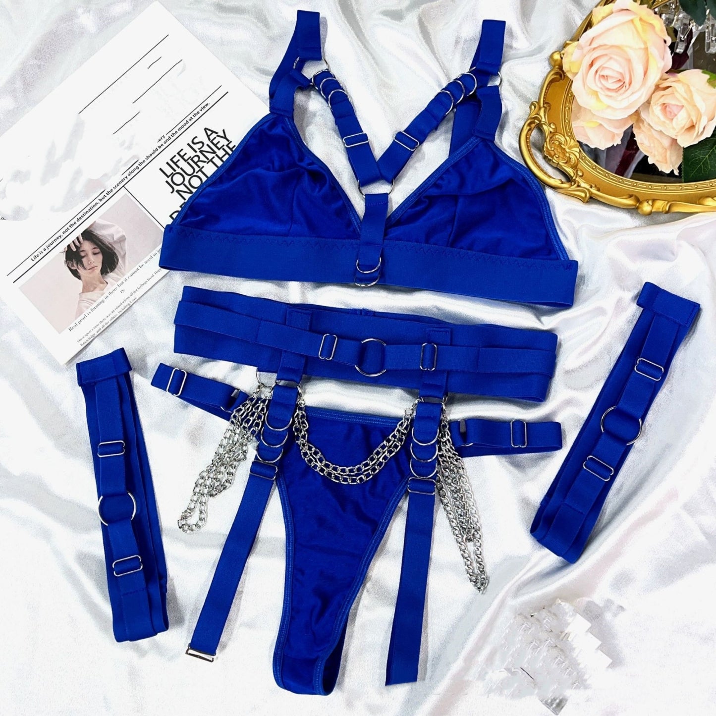 Sexy and alluring lingerie set with straps, metal chains, thong, and thigh-high stockings.